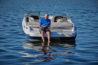 Ward reading on his boat and in front of his house on Lake Monona.
